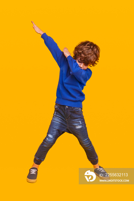 Energetic kid dancing on yellow background