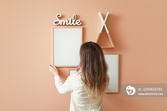 Woman hanging blank photo frames on wall