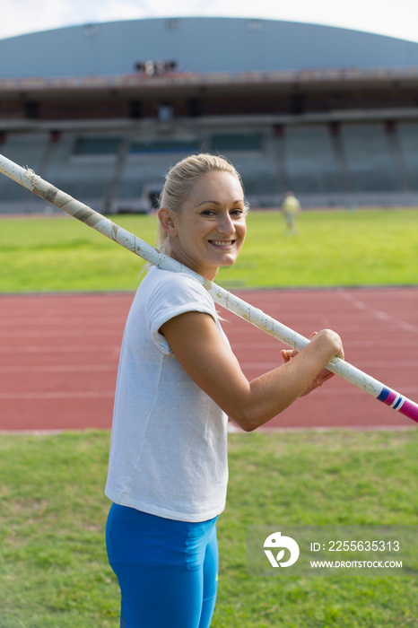 Portrait smiling female track and field athlete practicing pole vault