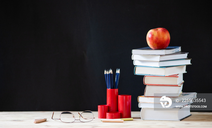 back to school concept pile of books against chalkboard