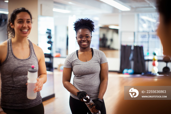 Happy female athletes talking while standing in gym