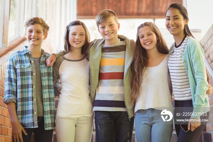 Portrait of happy students standing with arms around in corridor