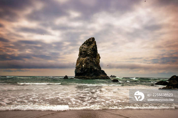 Rock formation amidst sea against cloudy sky at sunset