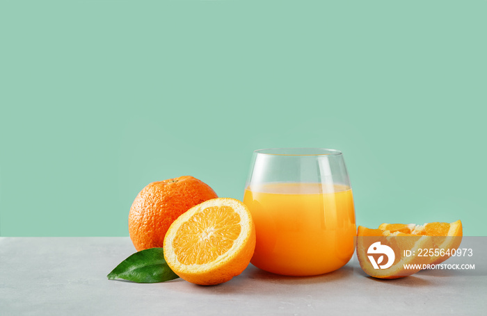 在时尚的薄荷水背景下，将橙汁放在装有橙子的玻璃杯中特写