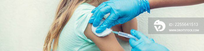 The doctor gives the child an injection in the arm. Selective focus.