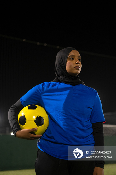 Portrait of female soccer player holding ball