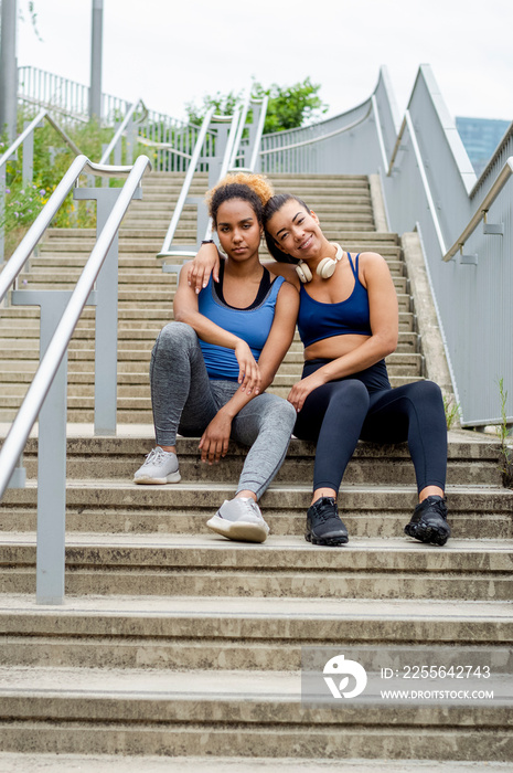 Sporty female friends sitting on stairs