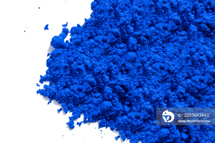照片右侧散落着蓝色颜料颗粒和粉末，从白色上方观看。