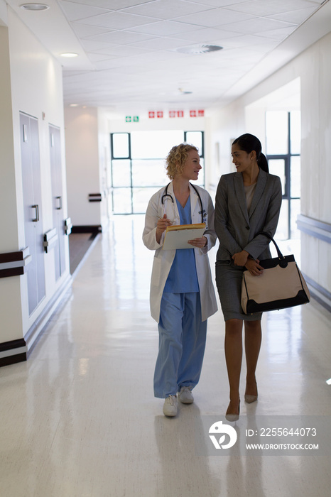 Female doctor and administrator walking in hospital corridor