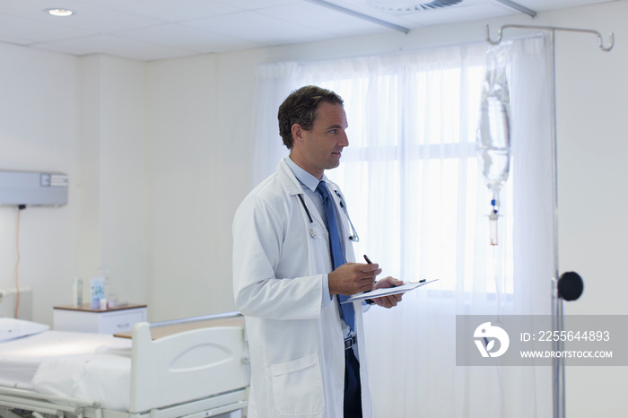 Male doctor checking IV drip in hospital room