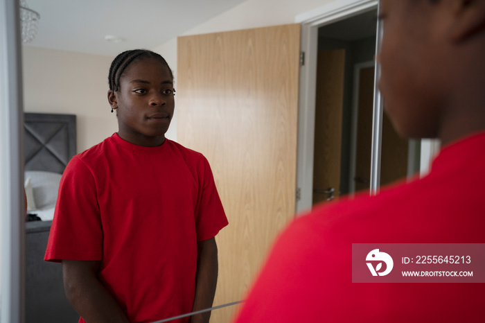 Teenage boy looking in mirror at home