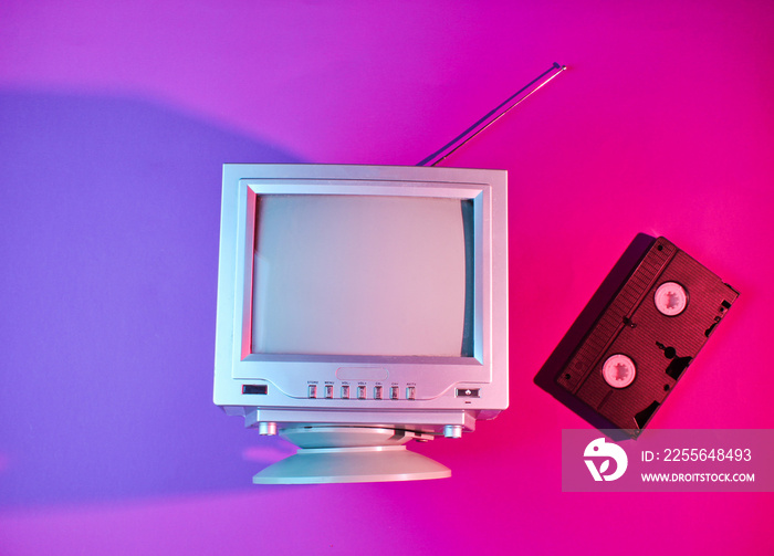 Retro wave, minimalism 80s concept. Retro TV with antenna, video cassette. Neon pink blue light. Top