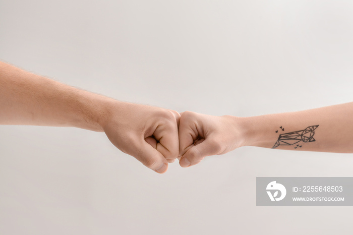 Man and woman making fist bump gesture on light background