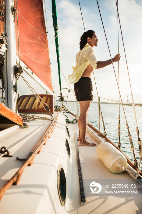 Mid-adult man sailing, looking at sea