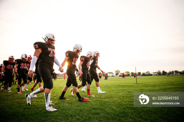 Football players (16-17) walking on playing field