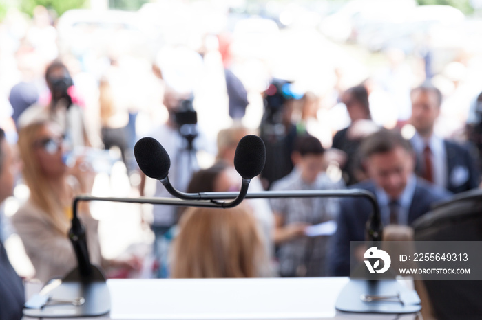 Microphone in focus at press or public event, blurred people in the background