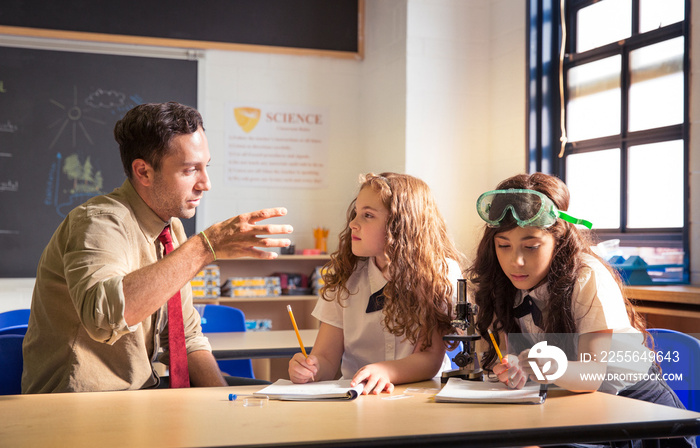 Teacher helping students (8-9) with science experiment