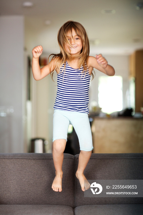 Girl (4-5) jumping on sofa