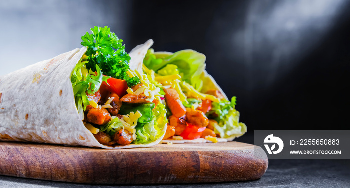 Tortilla with chicken and fresh vegetables on a cutting board