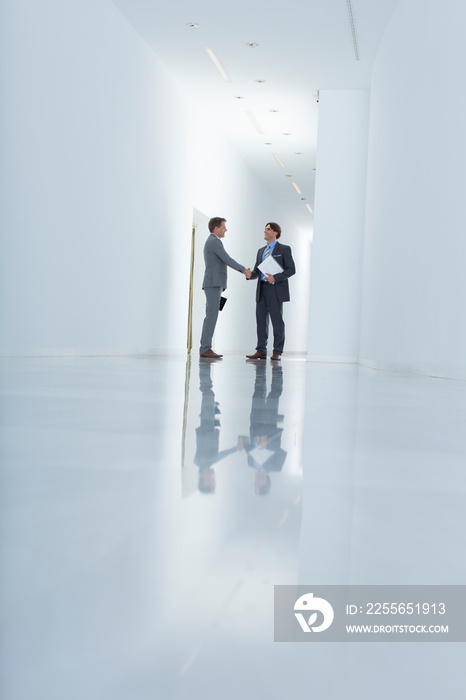 Businessmen shaking hands in modern office corridor