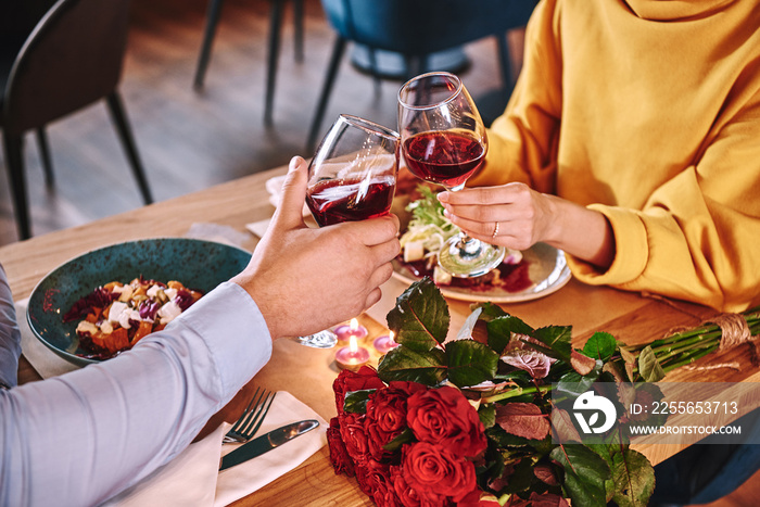 Happy moments. Close-up of couple holding red wine in restaurant