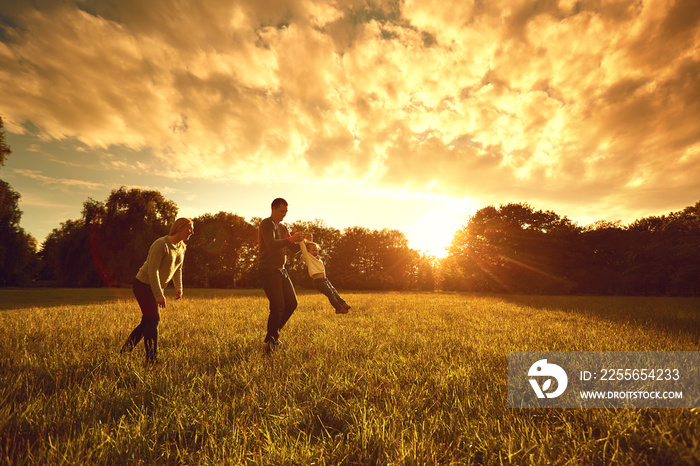 Happy family plays on the park at sunset.