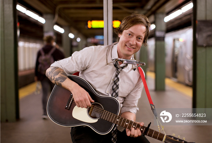 Portrait of street musician playing guitar in subway station