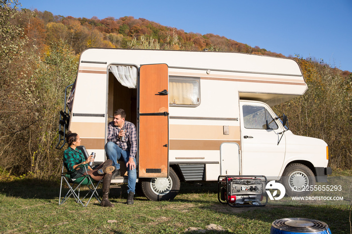 Man sitting on the stairs of his retro camper van in the mountains