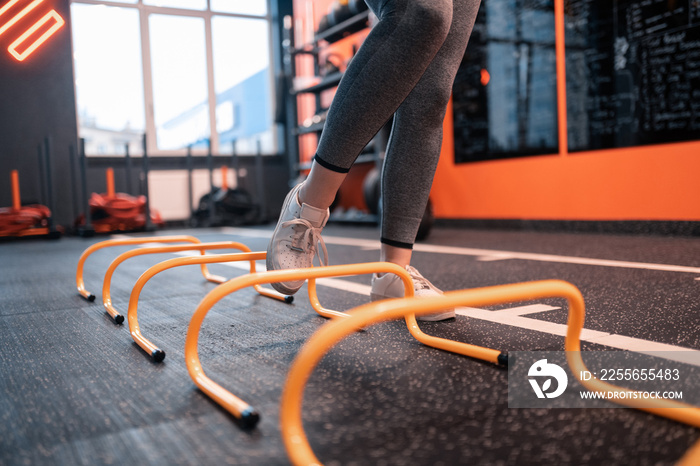 Close up of woman wearing white sneakers running with obstacles