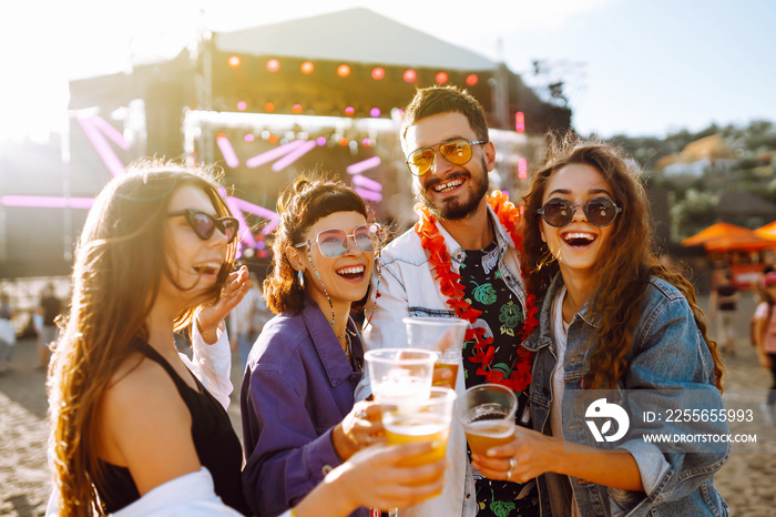 Young happy friends drinking beer and having fun at music festival together. Beach party, summer hol