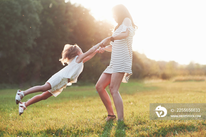 Holding by the hands and spinning around. Photo of young mother with her daughter