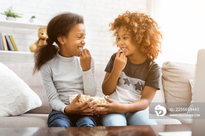 African-american friends eating popcorn, looking at each other