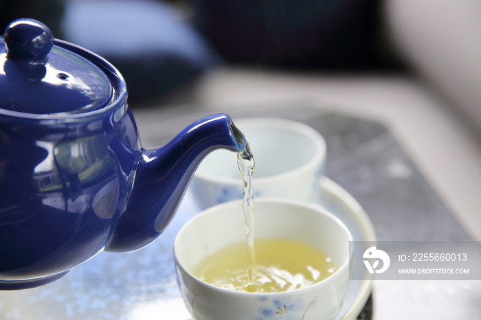 在近距离的中国和日本饮料中将茶倒入一杯茶中