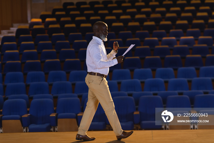 Businessman practicing and learning script while walking in the auditorium