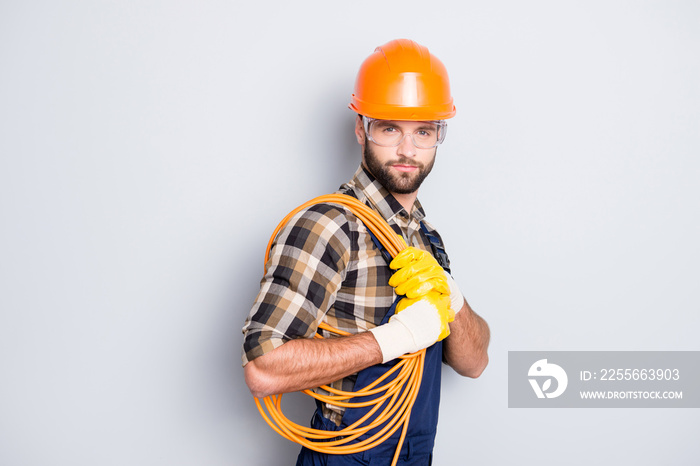 Portrait of trendy virile electrician in hardhat, overall, shirt is ready for work, having, holding 