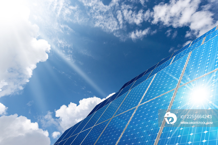 Large group of solar panels on blue sky with clouds and sun rays. Solar energy concept.