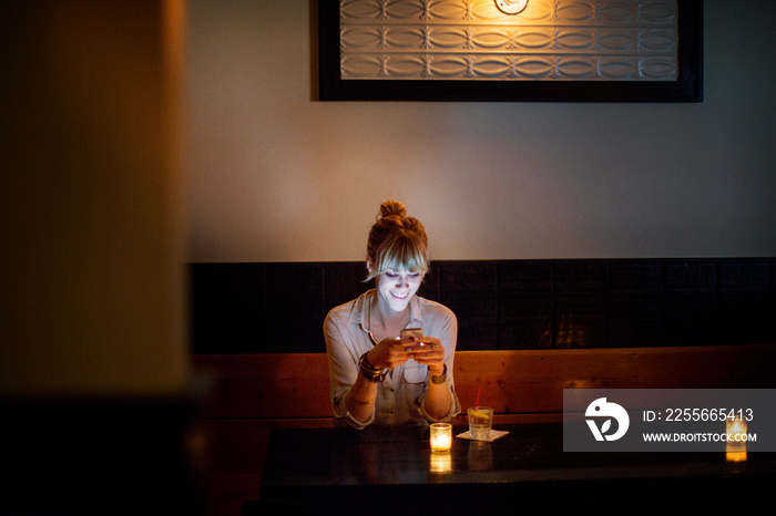 Young woman using mobile phone in restaurant