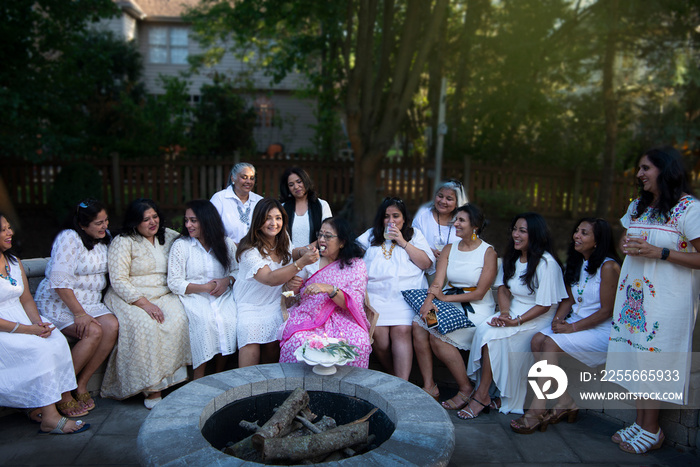 Woman feeding cake to her mother with her friends