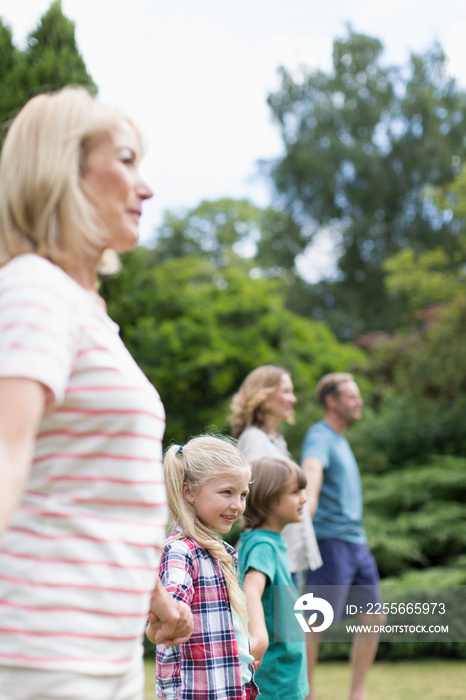 Multi-generation family holding hands in backyard