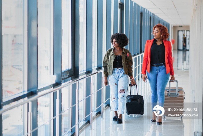 Two african girls with suitcases at the airport. The concept of travel and vacation.