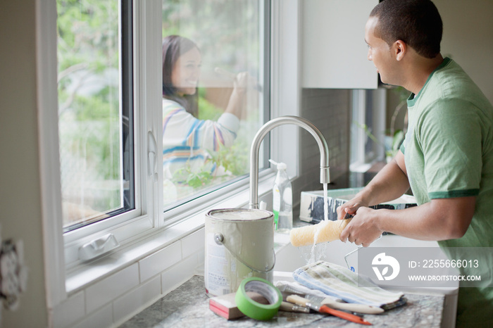 young adult man washing up painting tools