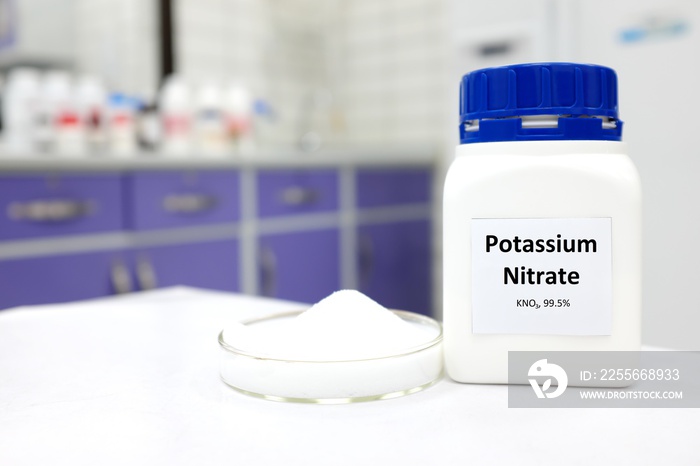 Selective focus of a bottle of pure potassium nitrate chemical compound beside a petri dish with sol