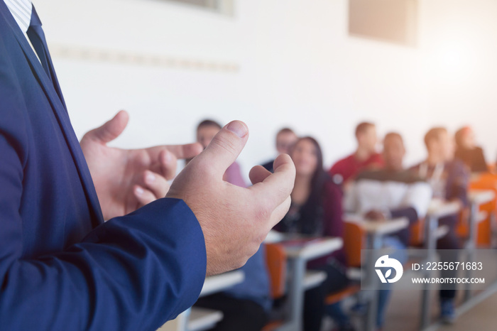 Male professor explain lesson to students and interact with them in the classroom. Selective focus o