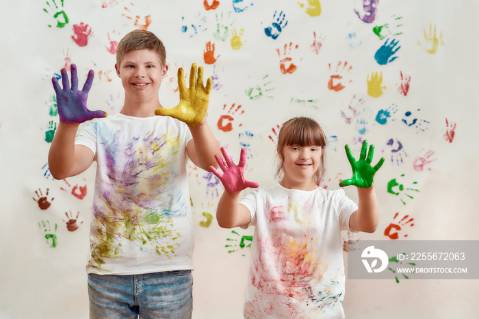 快乐的孩子，患有唐氏综合症的残疾男孩和女孩对着镜头微笑，展示他们的双手被画好了