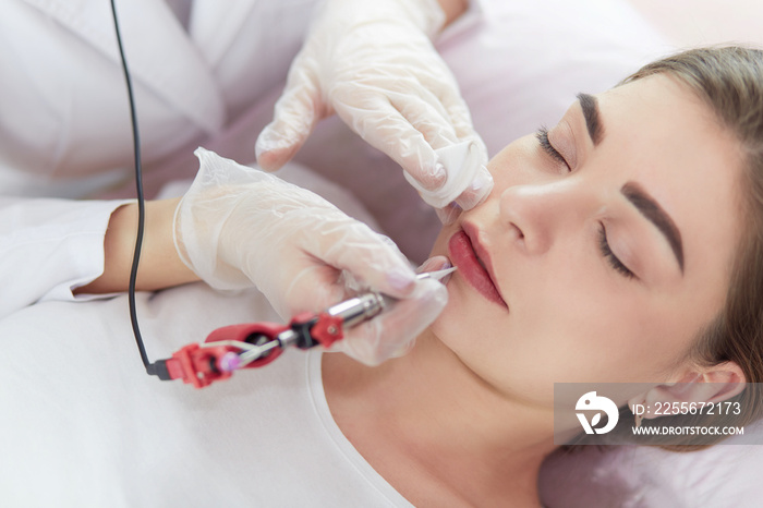 A young girl having red lips permanent makeup, micropigmentation