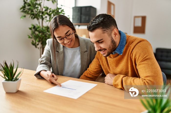 Couple smiling happy reading document at the office.