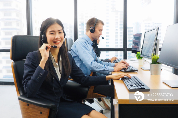 Beautiful Asian woman and her diverse colleagues smiling and giving thumbs up in call center work re