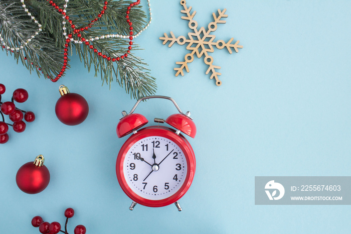 Christmas composition with  red alarm clock on the blue background. Top view. Copy space.