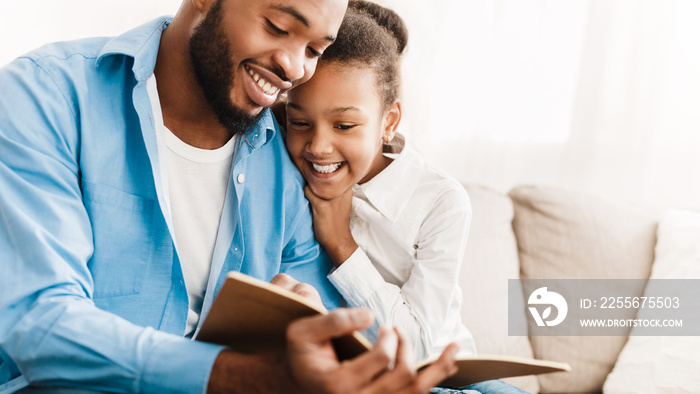 Father and daughter reading book together at home