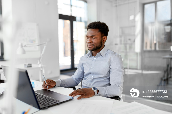 business, people and technology concept - african american businessman with laptop computer working 